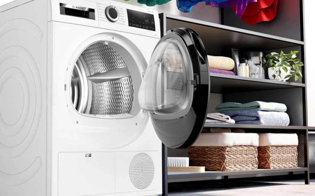 Heat pump tumble dryer in a modern utility room showing controls and drum